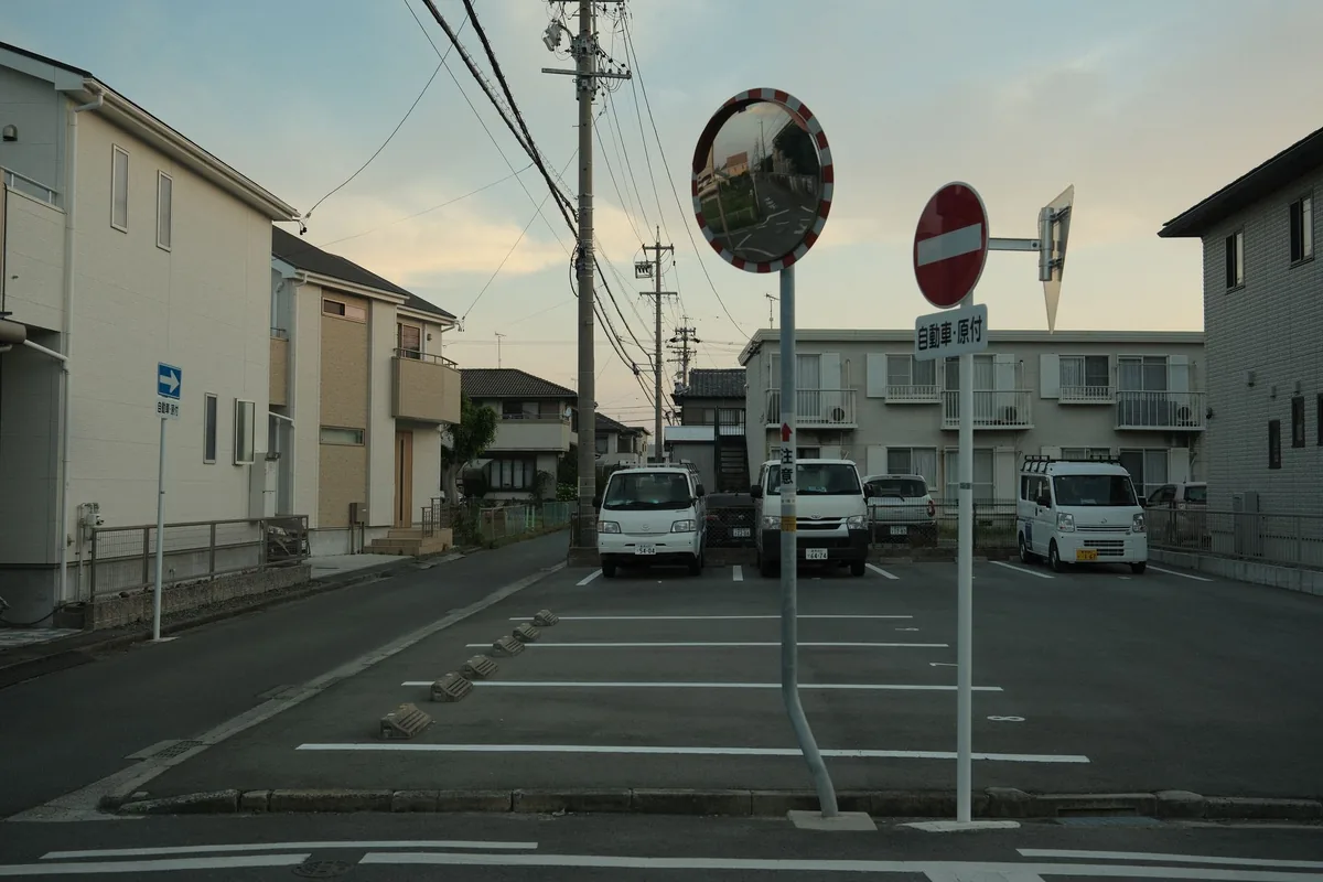 住宅が近接して建ち並ぶ住宅街の道路と、その脇の駐車スペース（イメージ写真）